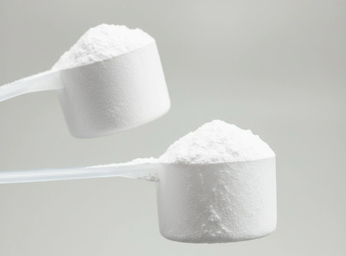 Two measuring scoops filled with vegan clear protein powder on a light gray background